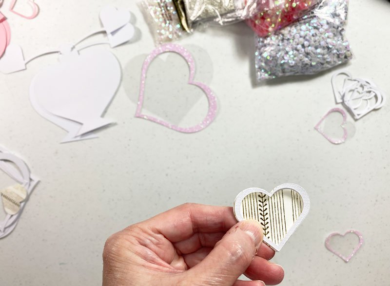 I glued the five heart layers to the top of the cream/gold cardstock hear to form the well for the sequins.